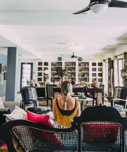 Mulher sentada num sofá de uma sala de costas para foto, observando a casa dela