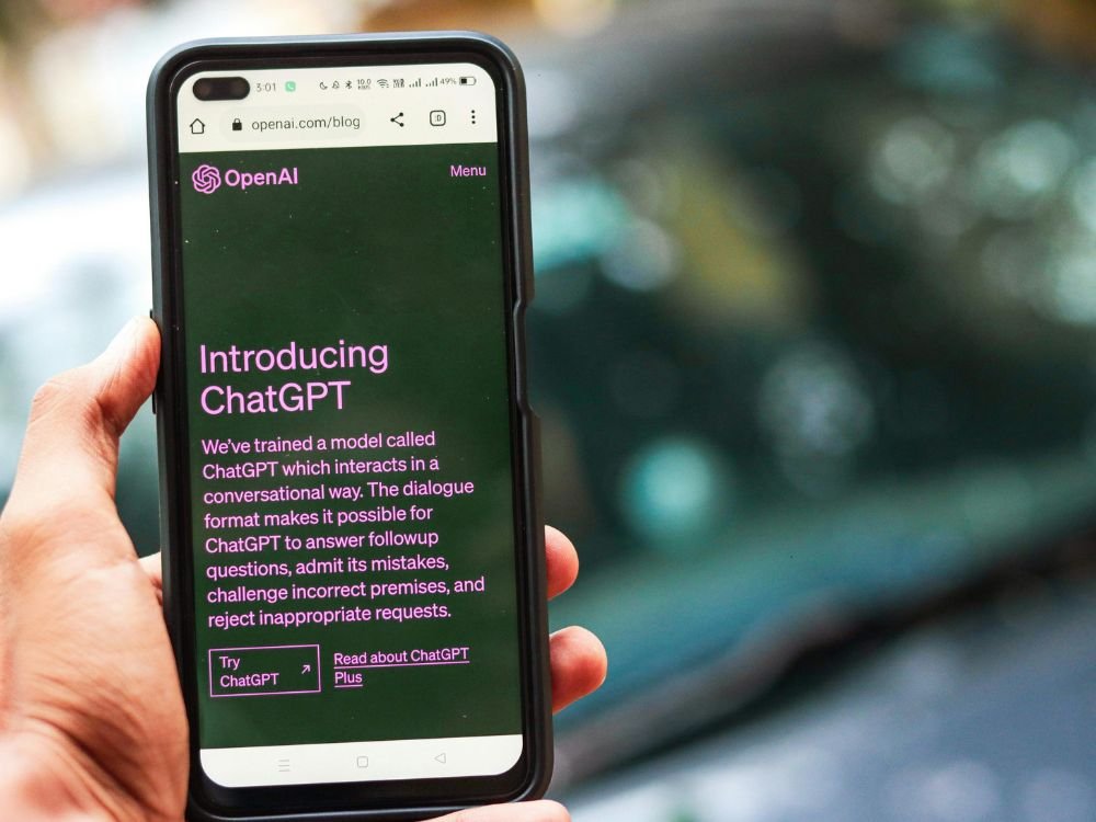 na imagem vemos a mão de uma pessoa segurando um smartphone e na tela vemos a página de introdução ao chatGPt, para o iniciante em IA começar com confiança
