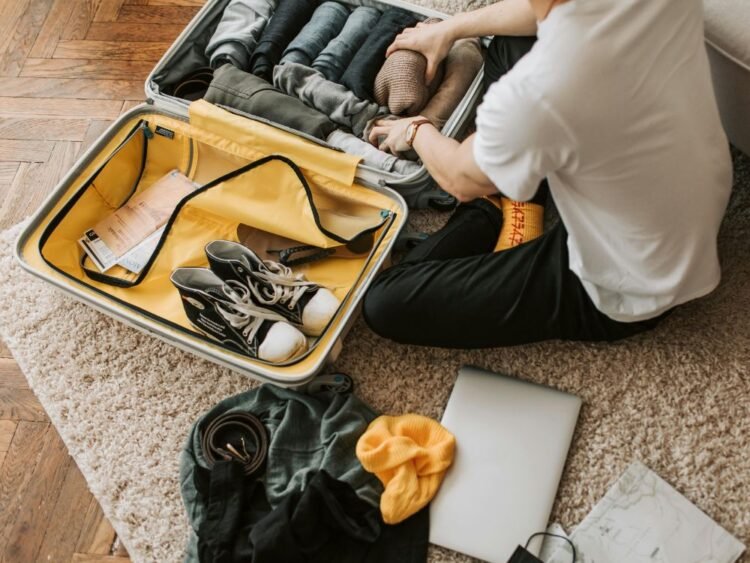 Homem organizando sua mala de viagem usando as dicas do artigo 'Mala pronta e Partiu!